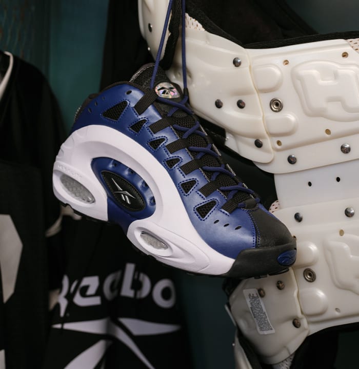 Side view of blue, black, and white Reebok shoes.